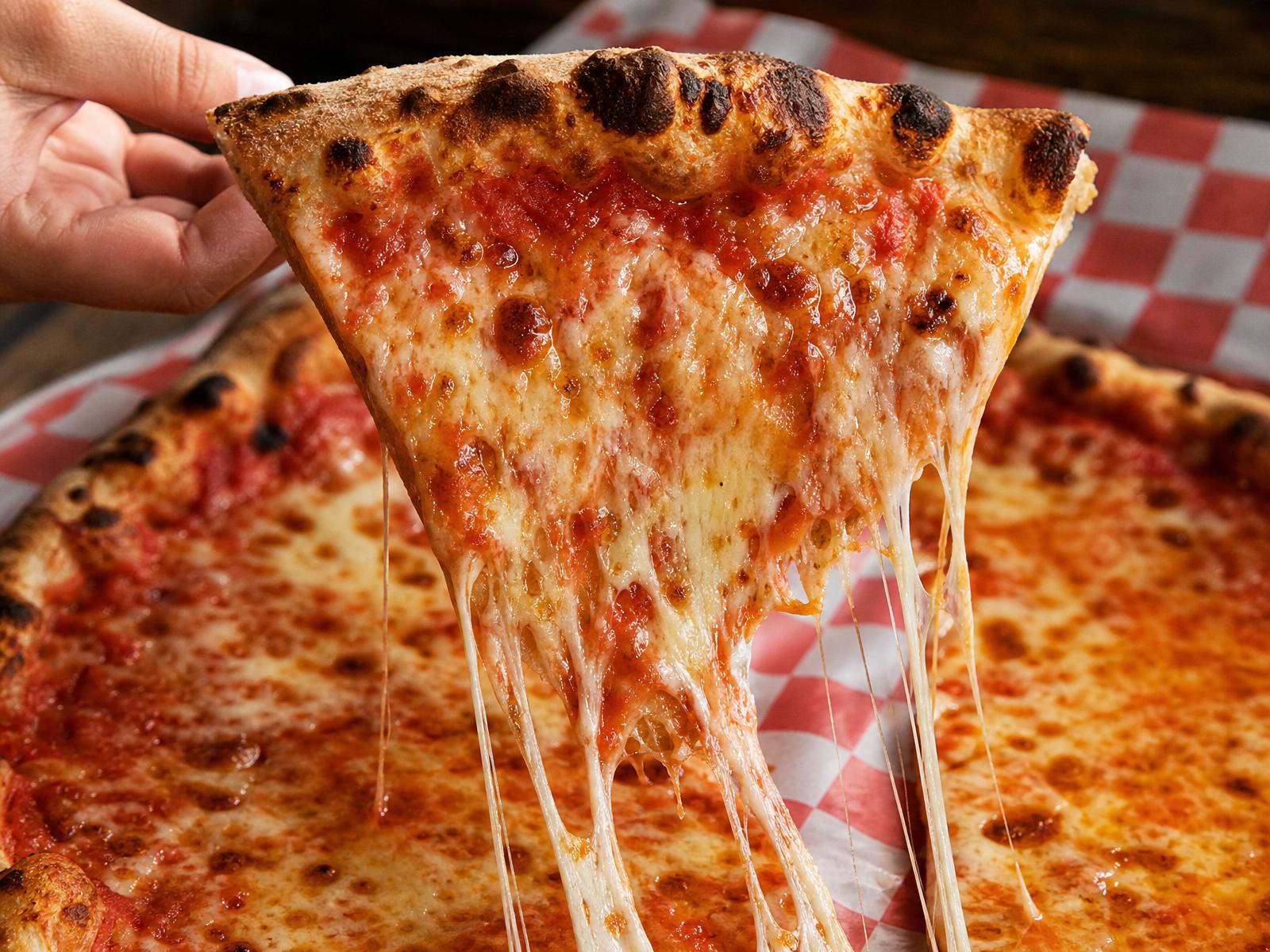 Huge New York pizza slice with a dramatic cheese pull